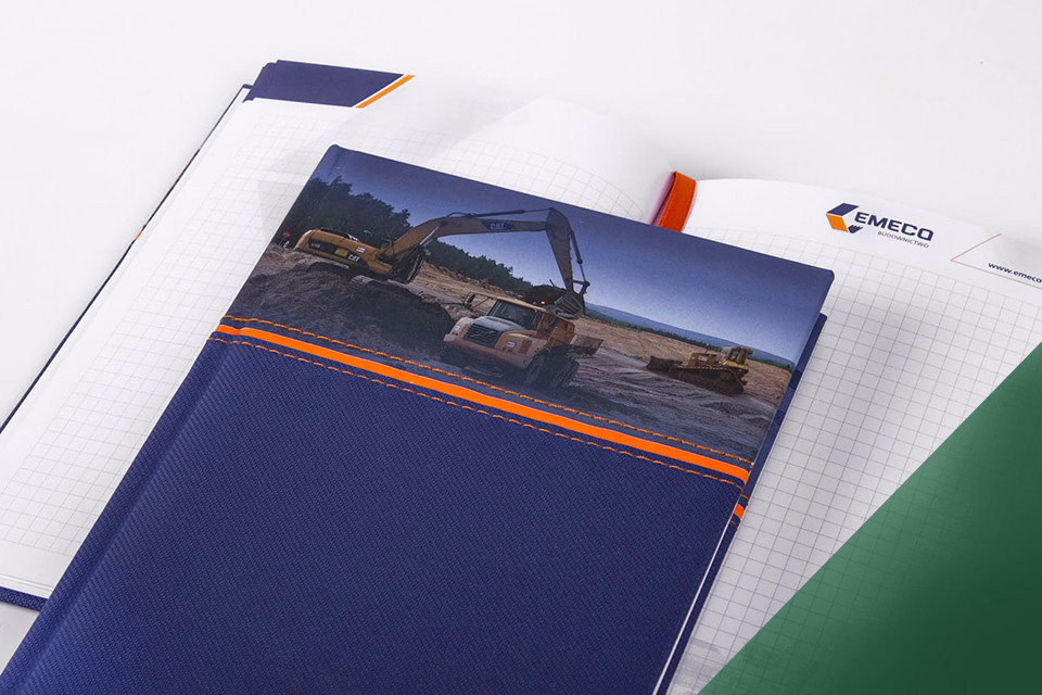 Duży notatnik reklamowy A4 z indywidualnie zaprojektowanym środkiem w kratkę z grafiką maszyn budowlanych 